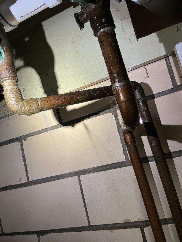 Responded to emergency call for continuous water spray from copper pipe connected to water softener in basement. Upon arrival, found corroded plumbing infrastructure with inoperable shut-off valves due to age and oxidation. Successfully isolated water supply by operating gate valves in the vertical pipe assembly, stopping the active leak and preventing further water damage to basement area. Identified extensive corrosion on older steel piping and deteriorated valve components requiring future replacement recommendations.