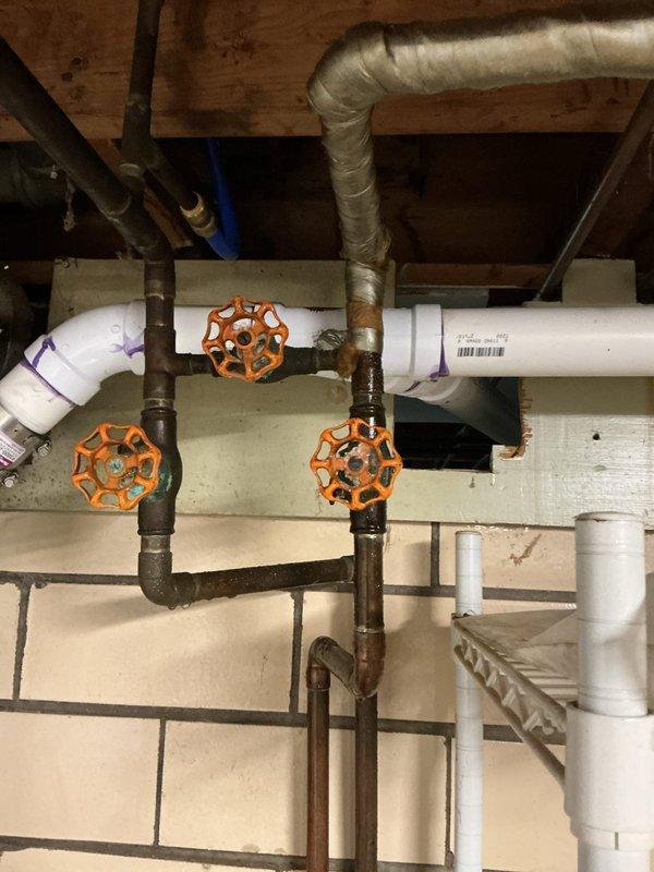Responded to emergency call for continuous water spray from copper pipe connected to water softener in basement. Upon arrival, found corroded plumbing infrastructure with inoperable shut-off valves due to age and oxidation. Successfully isolated water supply by operating gate valves in the vertical pipe assembly, stopping the active leak and preventing further water damage to basement area. Identified extensive corrosion on older steel piping and deteriorated valve components requiring future replacement recommendations.