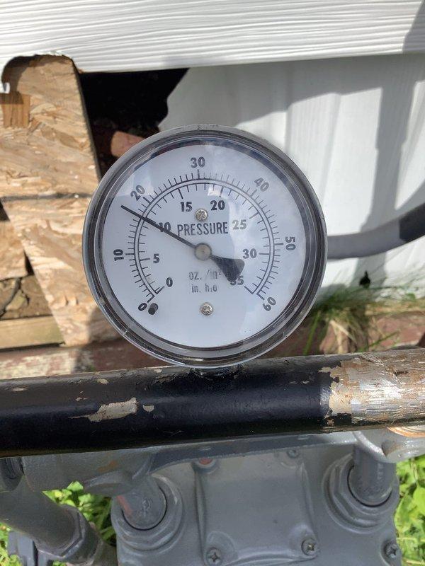 Responded to gas leak investigation following utility company detection of continued leak near meter. Performed pressure test on gas system to isolate leak location, with testing focused on pipes downstream from meter assembly. Inspection revealed severely corroded gas piping in crawlspace with compromised integrity, confirming leak source in piping connected to meter. Pressure gauge reading documented at approximately 5 units, indicating system pressure loss. Corroded metal pipe showing significant deterioration with rust patina throughout surface, connected to flexible yellow gas line. Crawlspace conditions noted with accumulated debris and moisture contributing to accelerated pipe corrosion. Testing confirmed utility company assessment that leak originates from meter-connected piping requiring replacement to restore system integrity and safety.