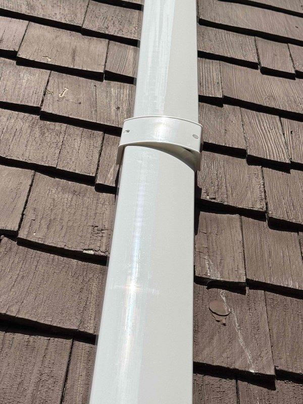 Returned to complete warranty repair by installing pipe couplings on vertical PVC vent penetration through roof and at interior junction point to prevent future leaks. Secured all piping with proper strapping and verified watertight connections at roof penetration and interior corner assembly.