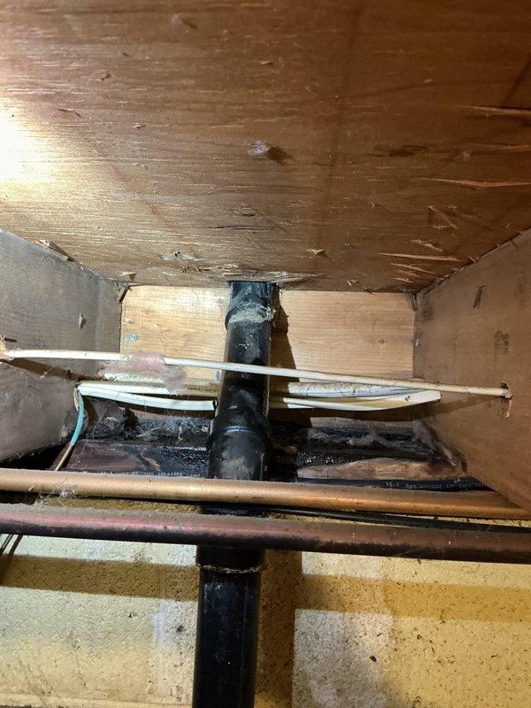 Responded to report of small leak at kitchen sink with water running outside of pipe to basement area. Upon inspection, identified leak in water supply line connection beneath sink. Examined plumbing infrastructure in basement crawl space, including copper water supply lines, vertical drain pipe, and horizontal piping secured with metal hangers. Inspected bathroom sink plumbing assembly featuring PVC drain system with P-trap configuration, flexible braided supply lines, and shut-off valves. Noted previous water staining on cabinet floor indicating past moisture exposure. Tightened connection fittings and secured supply lines to eliminate leak. Verified all connections were properly sealed and tested system for proper drainage and water flow.