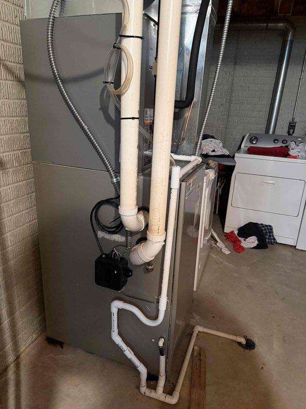 Completed first-time air conditioning and evaporator coil installation at residential property. Installed new outdoor condensing unit with proper electrical connections including 25-amp time-delay fuses (FLNR rated) in disconnect housing mounted on exterior wall. Indoor evaporator coil was installed in conjunction with existing furnace system in basement utility area, with appropriate refrigerant line sets and condensate drainage routed through floor penetrations. System startup performed, electrical connections verified, and all components tested for proper operation.