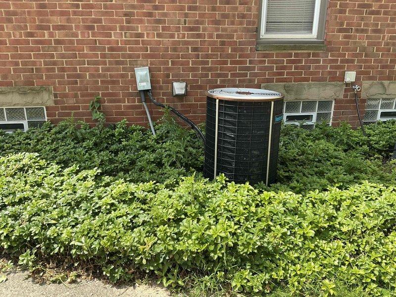 Completed full HVAC system replacement for residential property with 1990-era equipment. Installed new furnace unit in basement mechanical room with updated ductwork connections and electrical components, along with new cylindrical exterior air conditioning unit positioned against brick exterior wall. All systems tested and operational with proper electrical connections, conduit routing, and integration with existing infrastructure.