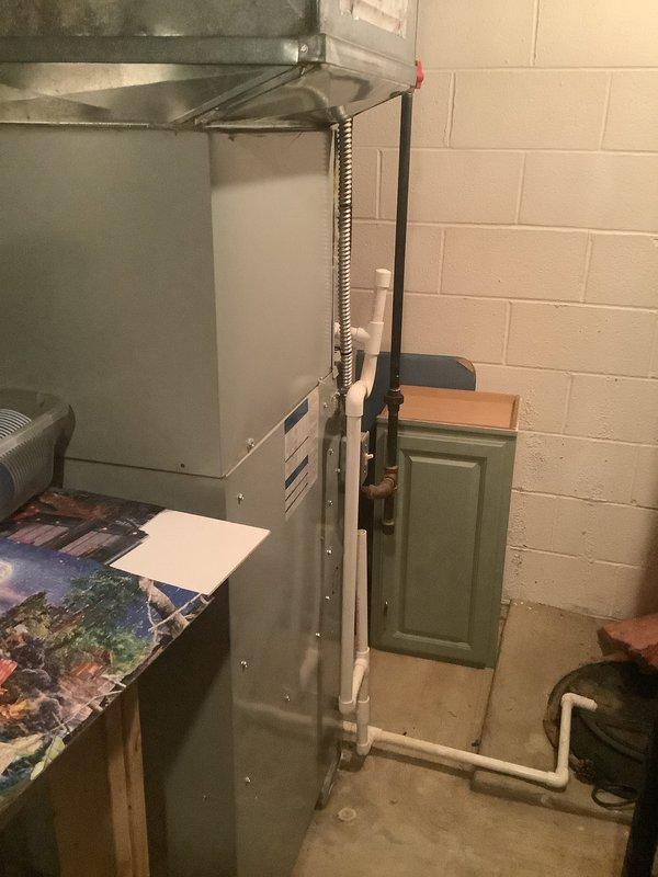 Conducted on-site evaluation for HVAC system replacement in residential basement utility area. Assessed existing gray metal furnace unit with vented panel and flexible metallic ductwork connections, along with white PVC piping configuration and associated ventilation components. Documented current system layout including exposed floor joists, insulated ductwork runs, and foundation wall clearances to provide comprehensive replacement estimate.