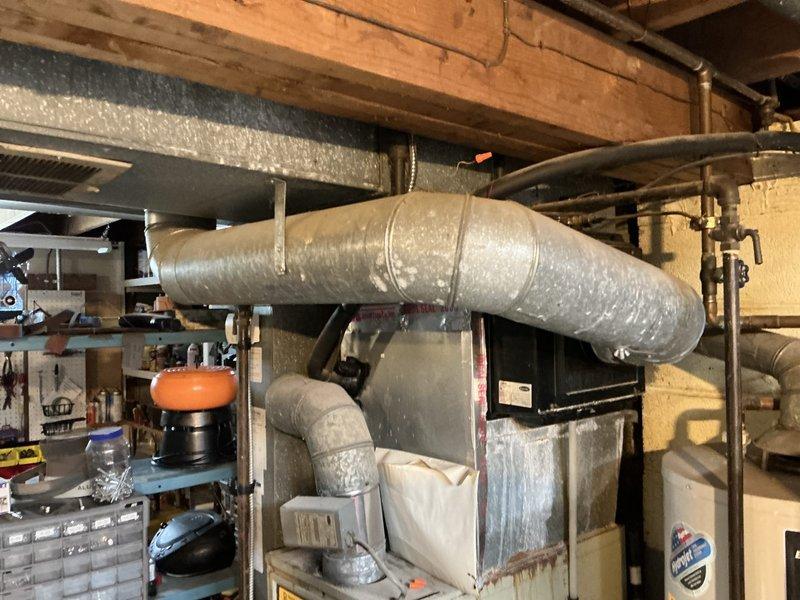 Conducted on-site evaluation for complete HVAC system replacement including 30-year-old gas furnace and 20-year-old air conditioning unit. Assessed existing basement-installed heating system with horizontal ductwork configuration and exterior condensing unit. Documented current equipment condition, measured installation space requirements, evaluated existing ductwork compatibility, and photographed mechanical room layout including furnace cabinet, flexible duct connections, and adjacent water heater positioning. Provided comprehensive replacement estimate for new high-efficiency furnace and air conditioning system to homeowner.