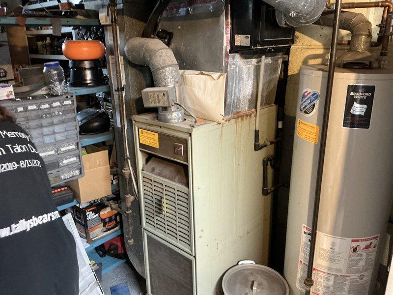 Conducted on-site evaluation for complete HVAC system replacement including 30-year-old gas furnace and 20-year-old air conditioning unit. Assessed existing basement-installed heating system with horizontal ductwork configuration and exterior condensing unit. Documented current equipment condition, measured installation space requirements, evaluated existing ductwork compatibility, and photographed mechanical room layout including furnace cabinet, flexible duct connections, and adjacent water heater positioning. Provided comprehensive replacement estimate for new high-efficiency furnace and air conditioning system to homeowner.