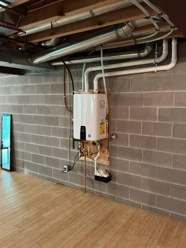 Replaced a leaking 50-gallon A.O. Smith gas water heater with a new Navien NPE-240A2 tankless unit, relocating and mounting it to the south wall near the electrical outlet. Installed a condensate pump with discharge line tied into the existing furnace condensation drain, vented the unit through the side wall, and ran a recirculation line connected to the kitchen hot water supply for improved efficiency and faster hot water delivery.