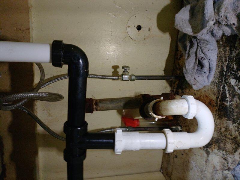 Completed plumbing estimate for kitchen sink replacement project. Assessed existing plumbing infrastructure beneath sink, documenting severely corroded metal drain pipes and aged water supply lines requiring replacement. Customer has already procured new sink fixture for installation. Evaluated current P-trap assembly, PVC drainage configuration, and deteriorating metal pipe sections showing significant rust and corrosion. Photographed existing conditions including compromised drain assembly, flexible supply lines, shut-off valves, and multi-generational plumbing components mixing newer plastic with older metal infrastructure. Provided comprehensive assessment for complete sink replacement and associated plumbing updates needed to bring installation up to current standards.