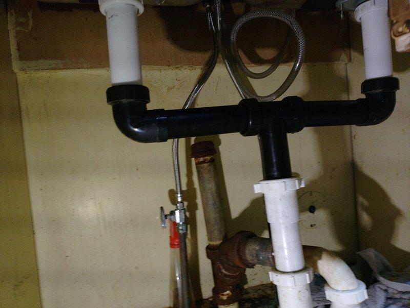 Completed plumbing estimate for kitchen sink replacement project. Assessed existing plumbing infrastructure beneath sink, documenting severely corroded metal drain pipes and aged water supply lines requiring replacement. Customer has already procured new sink fixture for installation. Evaluated current P-trap assembly, PVC drainage configuration, and deteriorating metal pipe sections showing significant rust and corrosion. Photographed existing conditions including compromised drain assembly, flexible supply lines, shut-off valves, and multi-generational plumbing components mixing newer plastic with older metal infrastructure. Provided comprehensive assessment for complete sink replacement and associated plumbing updates needed to bring installation up to current standards.