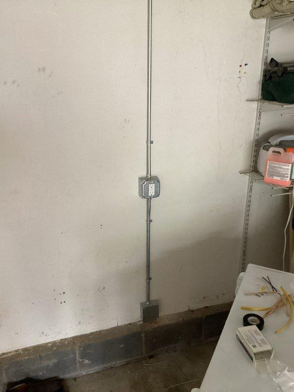 Installed two new dedicated electrical outlets in the garage on a shared circuit breaker from the main panel. Routed electrical wiring from the crawl space through the garage and into the attic space to reach the outlet location on the right wall, with surface-mounted conduit used for the final vertical run where concealed wiring was not feasible. One outlet was positioned to serve a freezer unit, while the second outlet was installed on the opposite wall to provide additional power access in the workspace.