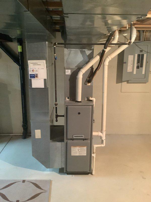 # HVAC Install - Complete System

Successfully completed installation of a complete HVAC system including 90% efficiency furnace, air conditioning unit, and humidifier in basement mechanical room. Installed new gray furnace unit with proper PVC venting system extending upward and connecting to ceiling ductwork infrastructure. Mounted and wired electrical components with dedicated panel installation. Ran copper refrigerant lines from air handler to outdoor AC unit with proper insulation and securing. Connected humidifier to system with appropriate water supply line. Installed black flexible conduit for electrical connections and control wiring between components. Verified all ductwork connections to existing infrastructure and ensured proper airflow distribution. Tested system operation including furnace ignition sequence, AC cooling cycle, and humidifier function. Confirmed proper condensate drainage through PVC piping system. Verified electrical connections at panel and equipment meet