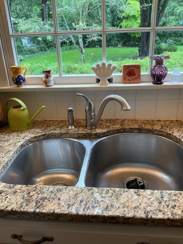 Provided quote for installation of customer-supplied kitchen faucet. Addressed callback regarding recently installed Moen faucet experiencing excessive water pressure issues. Assessed plumbing system and recommended pressure regulation adjustment to resolve high-pressure condition at fixture. Documented existing double-basin sink installation with functioning garbage disposal and standard P-trap drainage configuration.