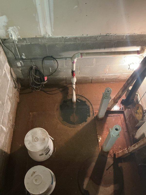 Responded to service call for malfunctioning sump pump located at the base of elevator shaft. Upon arrival, found standing water in the pump basin and surrounding floor area. Inspected sump pump system, including basin, discharge piping, and electrical connections. Identified pump failure preventing proper water removal from the pit. Assessed PVC discharge line routing and verified proper venting. Documented existing water damage and moisture staining on concrete floor surfaces. Photographed pump installation, piping configuration, and overall site conditions for record. Provided recommendations for pump replacement and potential improvements to drainage system to prevent future water accumulation in this utility area.