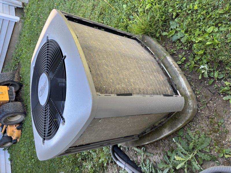 Completed preventive maintenance visit on residential air conditioning system. Performed visual inspection of outdoor condenser unit, noting weathered exterior surfaces and accumulated debris on mesh filter screen requiring attention. Unit operational with fan assembly functioning properly at time of service.