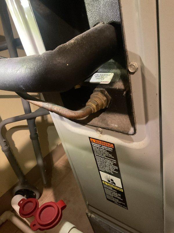 Completed routine MVP cooling maintenance visit on 28-year-old HVAC system. Performed comprehensive inspection of evaporator coil assembly, which showed moderate dust accumulation and visible rust-colored staining at coil housing junction, indicating potential condensate drainage concerns. Examined refrigerant line connections and insulation condition; noted deteriorated black foam insulation on suction and liquid lines with compression and age-related wear. All refrigerant line connections at unit entry point were inspected and found secure with brass fittings intact. System operational at time of service completion.