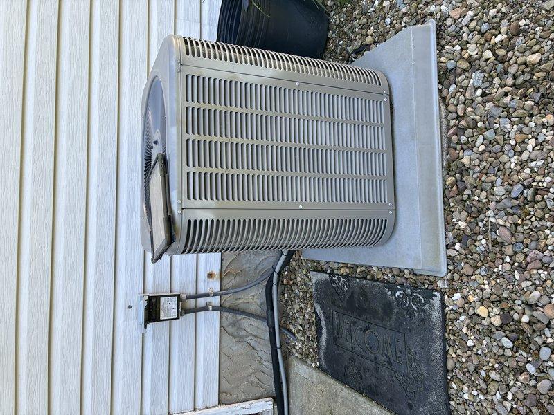 Completed preventive maintenance on residential air conditioning system. Performed electrical diagnostics with clamp meter, recording amperage readings of 23.8A and 20.5A on condenser unit. Inspected outdoor condenser unit positioned on concrete pad, verified proper airflow through top louvers, and confirmed all electrical connections and disconnect box are secure and operational.