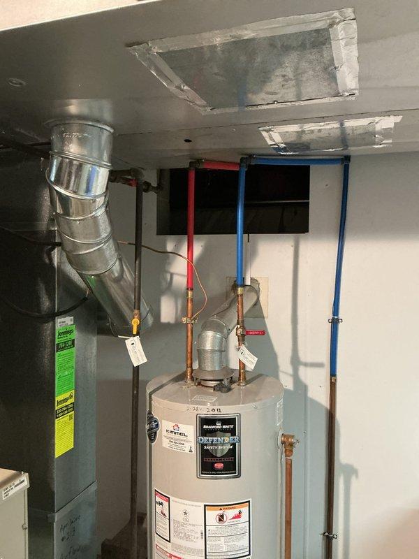 Responded to service call for non-functioning water heater with reported leak from overhead piping. Upon inspection of 50-year-old residential property, identified active water leak originating from supply piping above tanked water heater unit in basement utility area. Ceiling showed evidence of water damage and staining, indicating ongoing moisture intrusion. Assessed copper supply lines connected to water heater, noting red and blue color-coded hot and cold water connections. Repaired leaking pipe connection above water heater to eliminate water intrusion. Verified water heater operation restored to normal function following repair of supply line issue. Confirmed no additional leaks present and system operating properly upon completion.