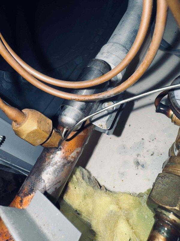 Performed leak search on commercial HVAC system and identified severe corrosion on copper refrigerant piping at elbow joint and connection fittings. Documented extensive rust and oxidation damage requiring immediate repair to prevent refrigerant loss and system failure.