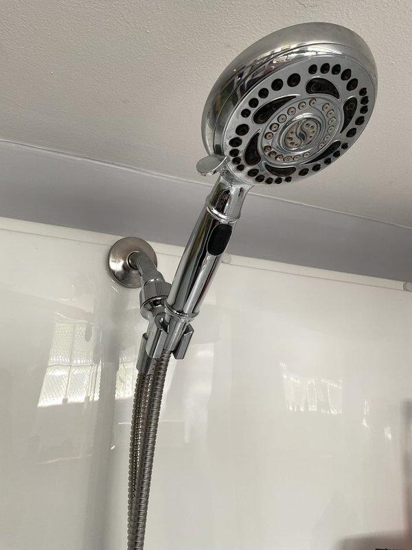 Responded to warranty callback for loose handheld shower head assembly. Upon inspection, found wall-mounted bracket and chrome holder secure with proper fastening. Verified flexible metal hose connection tight and showerhead functioning properly with no leaks detected. Confirmed installation stable and ready for continued use.
