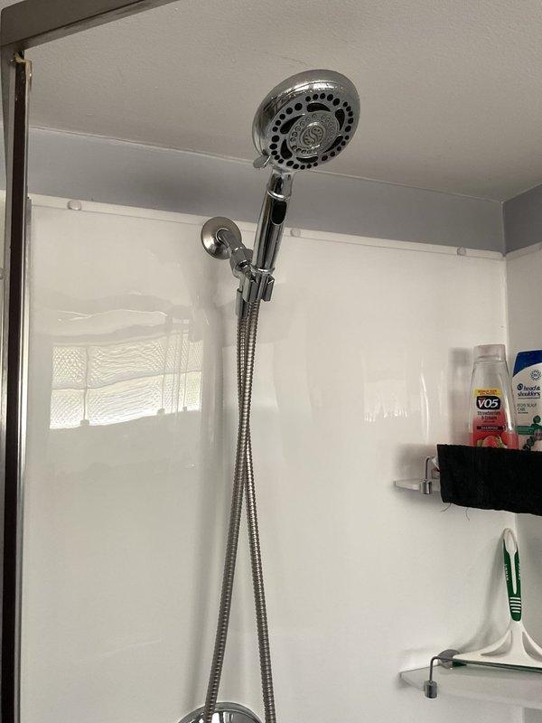 Responded to warranty callback for loose handheld shower head assembly. Upon inspection, found wall-mounted bracket and chrome holder secure with proper fastening. Verified flexible metal hose connection tight and showerhead functioning properly with no leaks detected. Confirmed installation stable and ready for continued use.