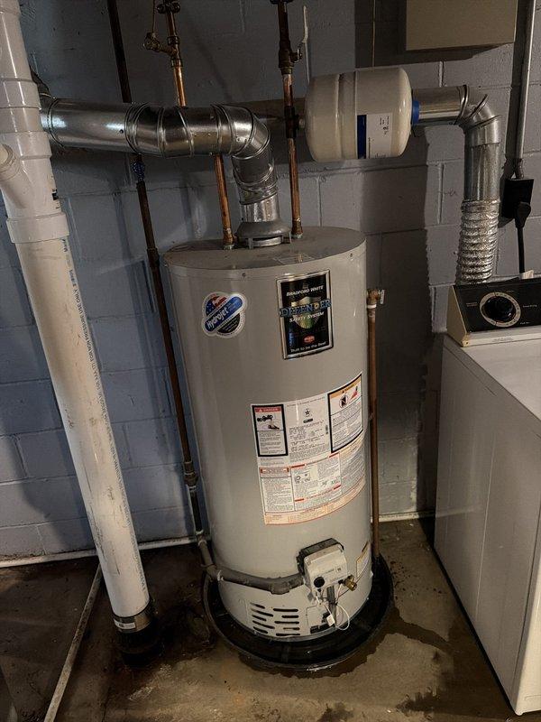 Responded to hot water leak from pipe on right side of water heater causing minor basement flooding in 73-year-old residence. Upon inspection, identified active drip from copper piping connection at top of unit. Tightened compression fitting on outlet pipe to stop leak, verified all connections secure, and inspected surrounding plumbing for additional issues. Confirmed water heater operating properly with no further leakage detected after repair.