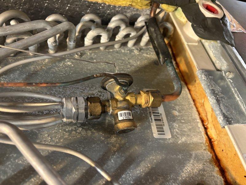 Completed MVP cooling maintenance visit on 4-year-old HVAC system. Performed comprehensive inspection of heat exchanger assembly, refrigerant lines, condensate drain system with PVC piping and red valve fitting, and electrical components. Documented system condition with internal cabinet photography showing serpentine coil configuration, copper refrigerant tubing, brass valve assembly with multiple connection points, and overall equipment operation within normal parameters.