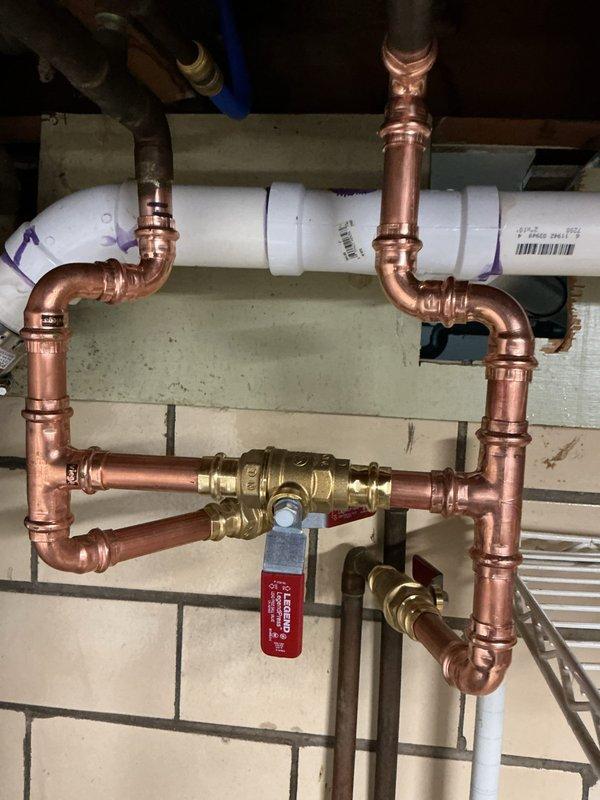 Responded to a pin hole leak at a copper elbow and pipe connection where all bypass valves were corroded and frozen. Removed the existing manifold and bypass system, then rebuilt the assembly using new copper pipe, press-fit fittings, elbows, and brass shut-off valves. Unsoldered existing tees and reconstructed water lines to restore proper function and eliminate leaks.