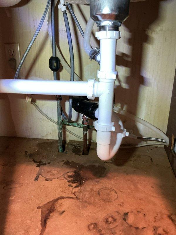 Repaired kitchen drain line leak extending into basement by removing dishwasher and accessing piping through wall cavity. Cut into existing drain pipe, rebuilt vertical drain assembly, and tied back into existing vertical stack. Replaced corroded basket strainer, P-trap, and trap waste assembly with new components including dishwasher tailpiece. Updated dishwasher shut-off valve and installed new supply line before reinstalling appliance. All drain connections tested and verified leak-free upon completion.