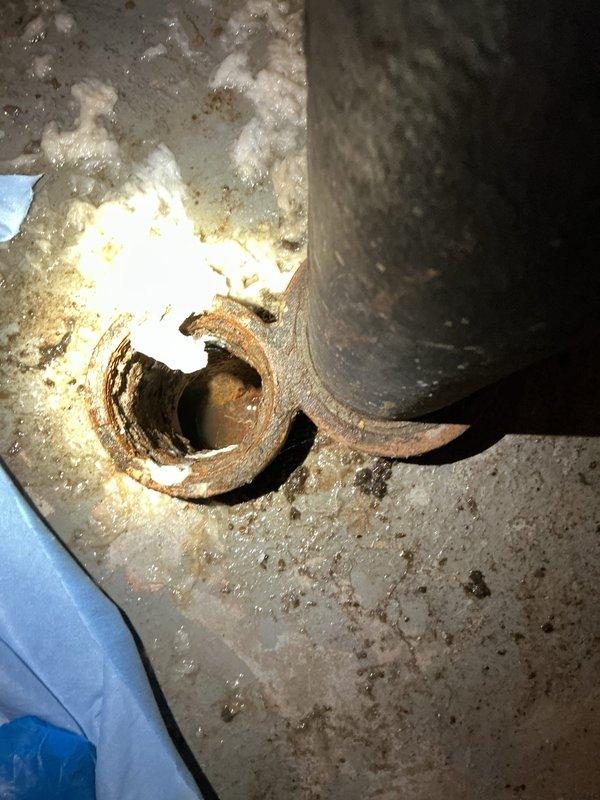 Responded to emergency call for mainline backup in basement. Upon arrival, located heavily corroded main drain cleanout with significant rust deterioration around the access point. Performed cleanout of mainline to restore proper drainage and eliminate backup condition. Noted extensive water damage, efflorescence, and mineral deposits on surrounding basement walls indicating history of drainage issues. Cleanout successfully cleared obstruction and restored flow through main sewer line.