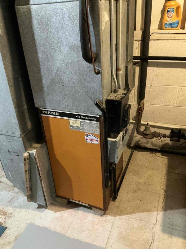 Completed in-home assessment for replacement of existing Tappan air conditioning unit and HVAC system in basement installation. Evaluated medium-sized residential heating and cooling system requirements for 1500-3000 square foot property with vertical upflow/downflow configuration. Provided estimate for Lennox A/C and natural gas furnace system replacement, including removal of existing equipment, new ductwork integration with current galvanized metal duct system, and proper venting for gas-fired appliance. Documented existing system conditions including aging Tappan AC unit with tan cabinet panel, current ductwork configuration against concrete block walls, and basement utility space layout for equipment access and installation planning.