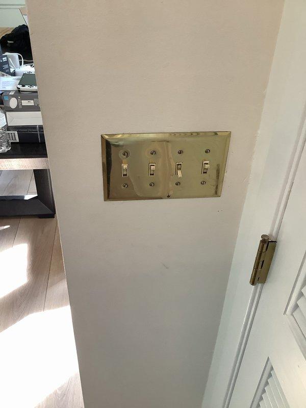 Replaced four toggle light switches in existing quad gang box using customer-supplied materials. Removed aged brass-toned switch plate and existing switches, installed new switches in metal electrical box, and verified proper operation of all circuits upon completion.