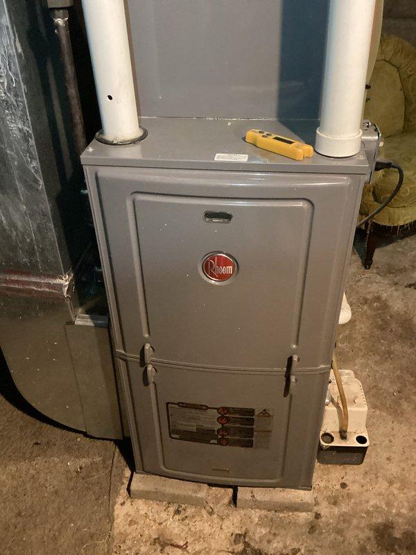 Completed MVP cooling maintenance visit on residential HVAC system over 10 years old. Performed comprehensive inspection of Rheem furnace unit located in basement utility area, verifying proper installation and operational status of vertical unit with dual PVC vent piping for intake and exhaust. Inspected exterior electrical components including disconnect box and meter socket mounted on building exterior, confirming secure connections and proper wire terminations with visible copper lugs. Documented system configuration and current condition of equipment through photographic records. All components found operational with no immediate service requirements identified during this routine maintenance inspection.