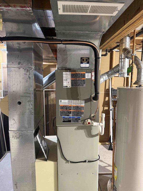 Completed first-time air conditioning installation including new outdoor condensing unit and indoor evaporator coil system. Installed new disconnect box with dual 25A fuses at outdoor unit location, verified proper electrical connections and conduit routing along exterior wall. Connected indoor coil to existing gas furnace in basement utility area, integrated with existing ductwork system to provide complete cooling capability to the residence.