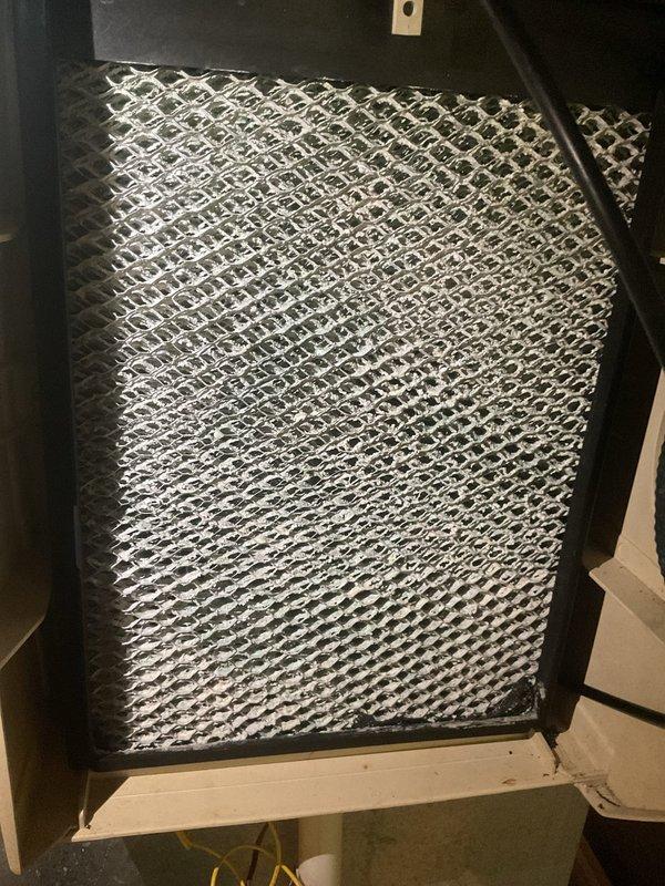 Completed preventive maintenance tune-up on 7-year-old air conditioning system. Inspected condensate drain line and PVC drainage connections, verifying proper flow and clearing any blockages. Examined air filter condition and housing assembly, confirming adequate airflow through the expanded metal mesh filter element and proper seating within the air handler frame.