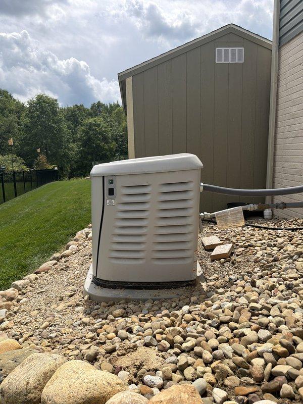 Responded to service call for recently installed Generac standby generator experiencing settlement issues. Upon arrival, confirmed unit was sinking into ground and no longer level on concrete pad. Assessed foundation and determined pad had settled unevenly, causing generator to tilt. Leveled generator unit by adjusting mounting position and ensuring proper support on concrete foundation. Verified unit stability and confirmed level placement using appropriate tools. Inspected surrounding gravel bed and decorative rock landscaping, ensuring proper drainage around installation area. Checked all electrical conduit connections running to building exterior and confirmed no stress or damage from settlement. Tested generator operation and verified all functions working properly after leveling adjustment. Installation now meets manufacturer specifications for proper mounting and positioning.