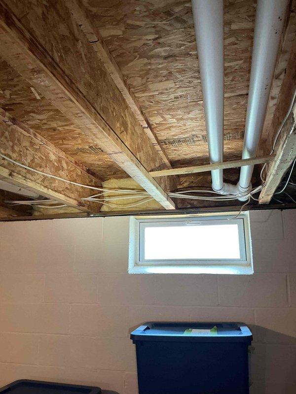 Conducted on-site electrical estimate for Kohler generator installation in basement utility area. Assessed existing infrastructure including exposed ceiling joists, OSB subflooring, and utility routing pathways with existing PVC plumbing and electrical conduits. Documented installation location near exterior window for proper ventilation requirements and photographed structural conditions to coordinate HOA approval process and finalize design specifications with customer.