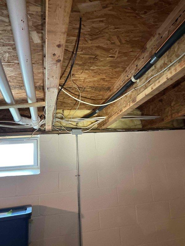 Conducted on-site electrical estimate for Kohler generator installation in basement utility area. Assessed existing infrastructure including exposed ceiling joists, OSB subflooring, and utility routing pathways with existing PVC plumbing and electrical conduits. Documented installation location near exterior window for proper ventilation requirements and photographed structural conditions to coordinate HOA approval process and finalize design specifications with customer.