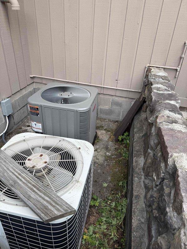 Completed full HVAC system installation including outdoor condensing units and indoor Lennox furnace. Installed three exterior AC condenser units on concrete pad against building exterior wall with proper clearances and drainage considerations. Interior installation included new Lennox furnace unit mounted in basement utility area with complete venting system using white PVC exhaust piping, copper refrigerant lines with insulation, black metal conduit for electrical connections, and dedicated electrical panel. All components properly secured to concrete block wall, system tested and verified operational.
