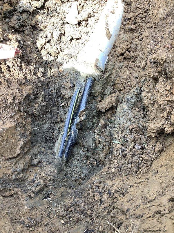 Underground service wire repair completed after damage caused by third-party fiber optic installation. Excavated area near exterior utility box to locate and access broken conductor, performed underground splice using approved materials and methods to restore electrical service. Backfilled excavation and restored yard area upon completion.
