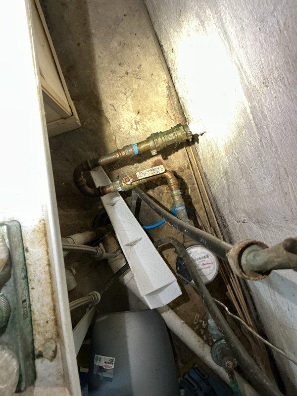 Responded to emergency call for water main line break with active water spraying from front yard to street. Upon arrival, conducted thorough assessment of the plumbing system including inspection of interior utility space housing pressure relief valves, connecting hoses, and pressure vessel components. Identified compromised main line requiring repair work. Documented extensive water damage to interior wall cavity with evidence of pipe deterioration and structural compromise. Photographed affected areas including mechanical room components and damaged wall section showing water staining and material degradation. Provided detailed estimate for necessary main line repairs to resolve active water leak and prevent further property damage.