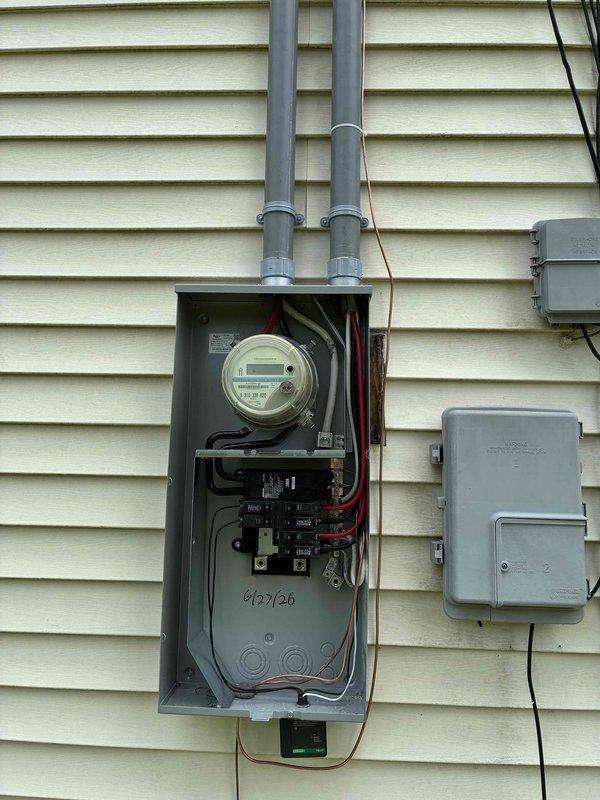 Upgraded electrical service to 200 amp exterior installation with disconnect and 8-space panel mounted on exterior wall. Installed two 90 amp breakers to independently feed existing garage panel and closet subpanel, with junction work completed in attic space above garage. Installed two 8-foot ground rods and updated waterline grounding connection from basement to new exterior disconnect, ensuring proper system grounding per code requirements.