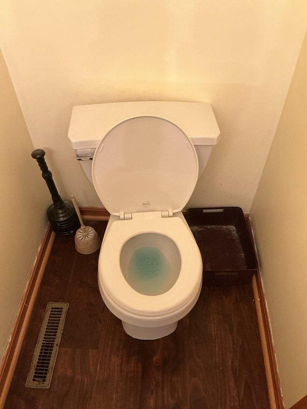 Responded to reported "toilet rain" issue at 20-year-old residential property. Upon arrival, removed toilet tank lid and conducted internal inspection of flush mechanism components. Found aged internal parts with significant mineral deposits, rust staining, and discoloration throughout tank interior. Identified deteriorated flapper valve, fill valve assembly with float ball, and flush handle mechanism showing signs of wear consistent with original installation age. Documented existing conditions of tank components including corrosion and mineral buildup affecting proper operation. Photographed toilet bowl with cleaning product present and complete tank interior showing all mechanical components requiring attention for proper flush cycle operation.