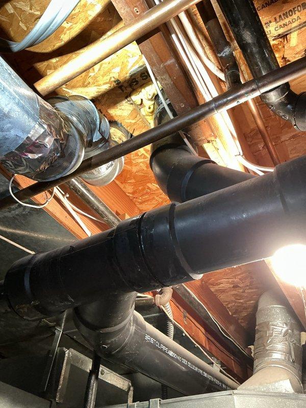 Responded to water leak emergency involving black pipe in attic/crawl space area. Upon arrival, located active leak creating significant water accumulation on floor. Inspected overhead plumbing system including black drainage pipes, copper water supply lines, and HVAC ductwork in confined space between joists. Documented conditions with photos showing pipe configuration and leak source area. Addressed leak issue and verified proper operation of affected plumbing components.
