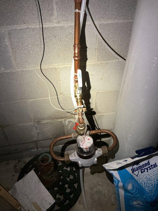 Responded to emergency service call for outdoor spigot that would not shut off. Located and identified the interior shut-off valves in the basement that control the exterior hose bibs, which were previously unknown to the homeowner. Successfully shut off water supply to the malfunctioning outdoor spigot using the brass shut-off valves mounted on the wooden plate near the main water supply line, stopping the continuous water flow and resolving the immediate emergency.