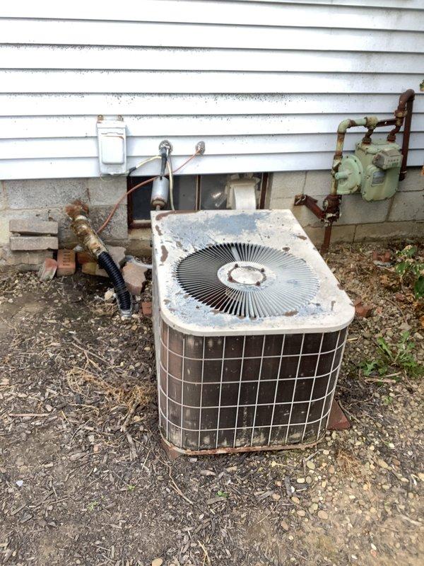Completed estimate for replacement of 20+ year old residential air conditioning system experiencing no cooling condition due to R-22 refrigerant leak. Inspected outdoor condenser unit showing significant age-related deterioration, weathering, and corrosion on copper refrigerant lines and connections. Evaluated indoor furnace and coil system in basement mechanical room. Documented existing equipment condition through photographs and provided replacement options for obsolete R-22 system.