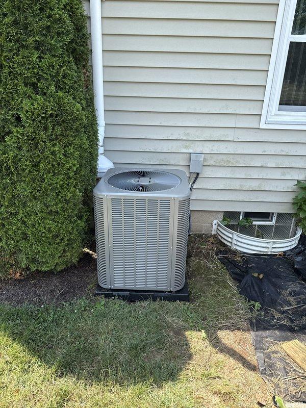 Completed installation of new air conditioning condenser unit and evaporator coil system at residential property. Mounted outdoor condenser unit on rubber isolation pad against exterior wall with proper clearances, installed brass service valves with locking caps on refrigerant lines, and ran copper lineset with foam insulation between indoor and outdoor components. Connected PVC condensate drain line from evaporator coil through exterior wall, secured all refrigerant connections, and verified proper system operation upon startup.