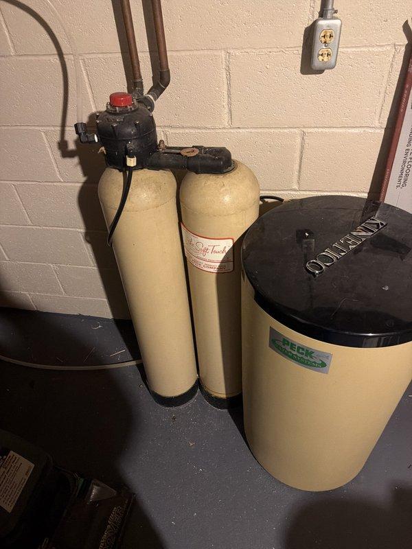 Responded to service call for non-functioning water softener system that was completely dried up with unknown age. Upon inspection, assessed three-tank water treatment configuration including dual filtration/conditioning tanks and demand-style brine tank with black control valve assembly. System showed signs of age with typical wear on copper supply lines, brass fittings, and control components. Documented existing installation conditions including electrical connections, plumbing configuration, and equipment status for customer review and future service recommendations.