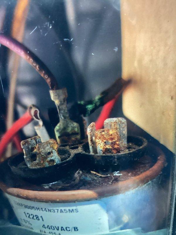 Responded to service call for non-operational air conditioning unit. Upon inspection, discovered heavily corroded dual-run capacitor with significant rust and oxidation on terminals and blade connections. The capacitor exhibited advanced deterioration due to moisture exposure, compromising electrical connections and preventing proper system operation. Replaced failed capacitor with new unit rated at 440VAC, ensuring all wire connections were secure and properly seated on terminals. Verified system startup and confirmed air handler operation with normal amperage draw. Unit returned to full cooling capacity.