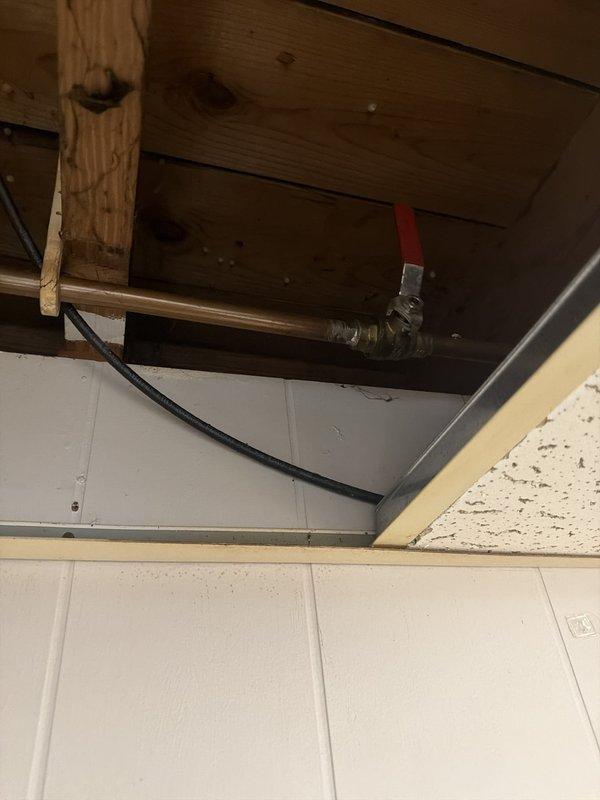 Responded to report of ceiling leak near window to determine source. Upon investigation, accessed ceiling cavity and inspected exposed plumbing lines and structural components. Identified copper and galvanized piping with shut-off valve in ceiling space above affected area. Examined pipes, fittings, and connections for signs of active leaks, moisture damage, or deterioration. Documented conditions of exposed plumbing system and ceiling infrastructure for assessment. No active pipe leaks observed at time of inspection; recommended monitoring area for further water intrusion to determine if source is plumbing-related or exterior building envelope issue.