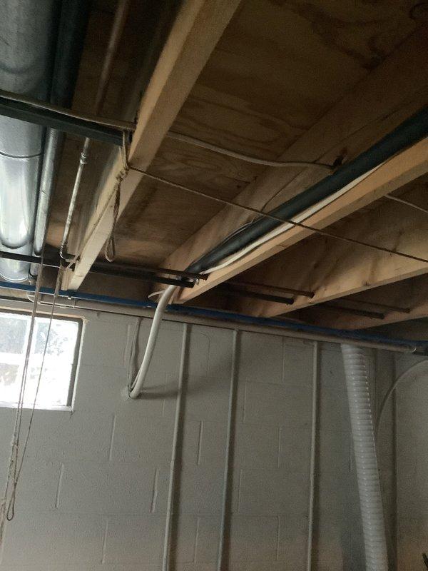 Conducted comprehensive assessment of 27-year-old residential air conditioning system found to be low on refrigerant. Inspected outdoor condensing unit positioned against brick wall foundation and evaluated basement ductwork and mechanical systems. Provided replacement estimate for aging HVAC equipment that has reached end of service life.